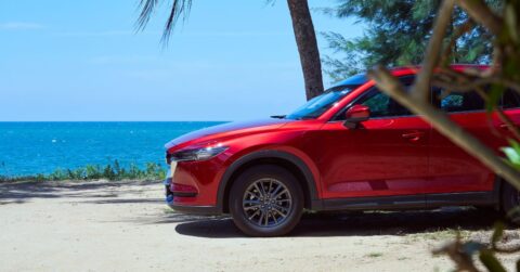 A red car parked at the beach area.