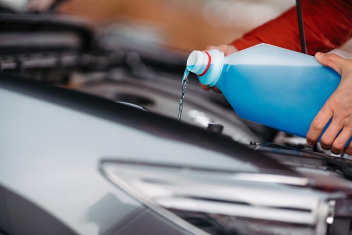 Filling a windshield washer tank with an antifreeze in winter cold weather.