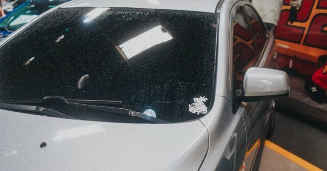 A silver car with wet windshield inside of a garage