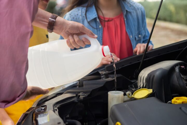 Close-up of Man Pouring Windshield Washer Fluid into the Container in a Car.