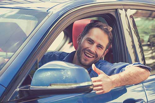 Windshield replacement customer in car with thumbs up.