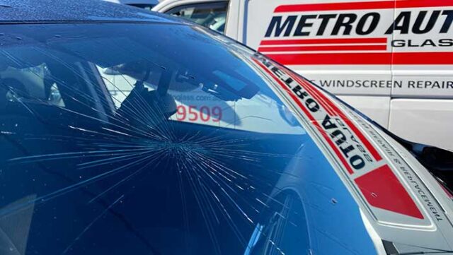 Cracked windscreen glass with Metro Auto Glass van in background