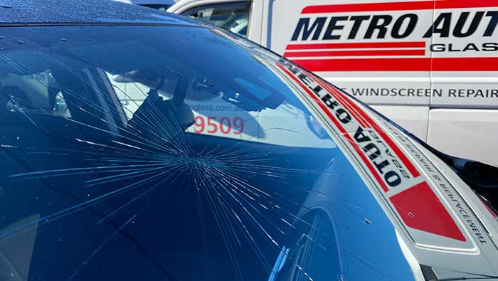 Cracked windscreen glass with Metro Auto Glass van in background