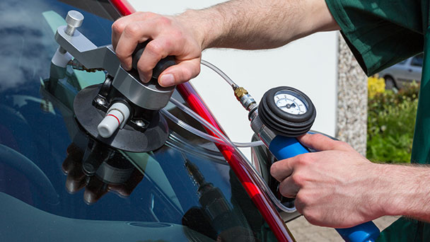 Windscreen repair technician injecting resin into chip.