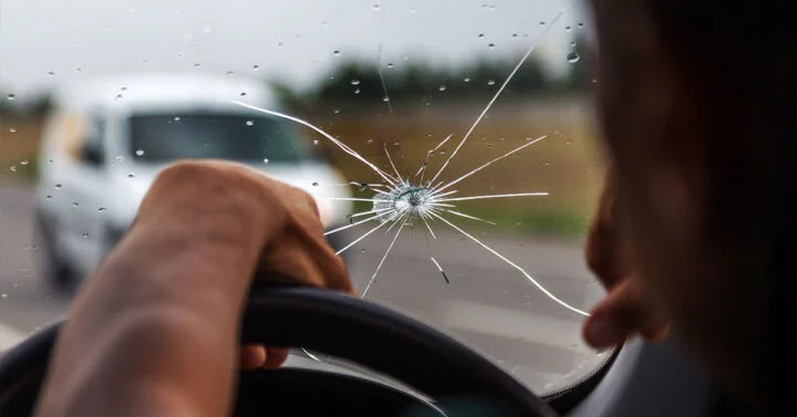 Driving with a large chip and cracks on driver side of windscreen.