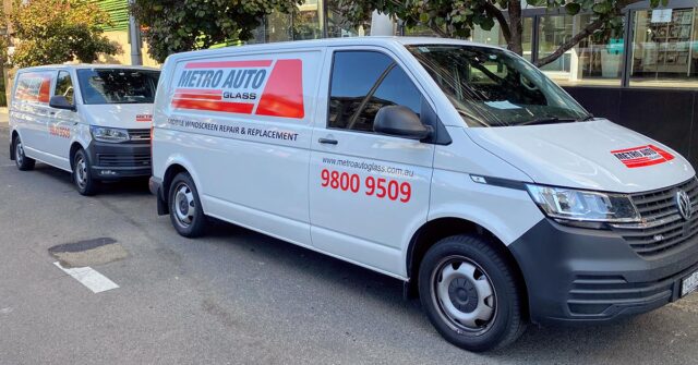 Two Metro Auto Glass branded vans parked on the street in a row.