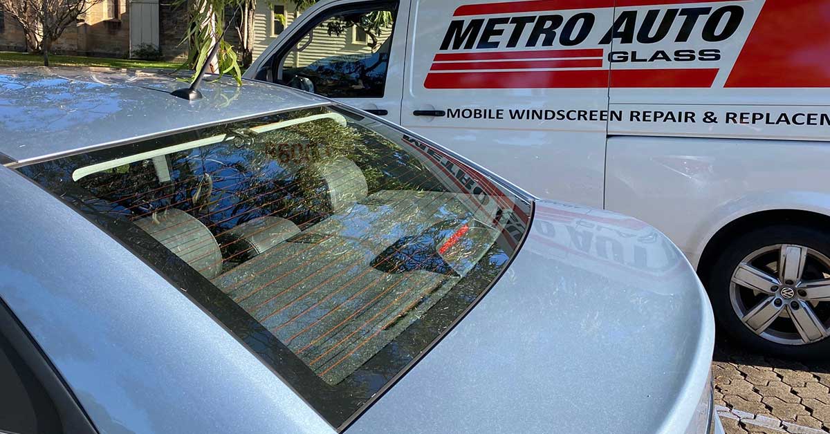 Close up of a rear window with Metro Auto Glass van in the background.