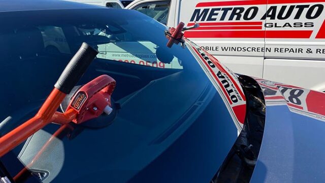 New windscreen glass being installed with Metro Auto Glass van in background