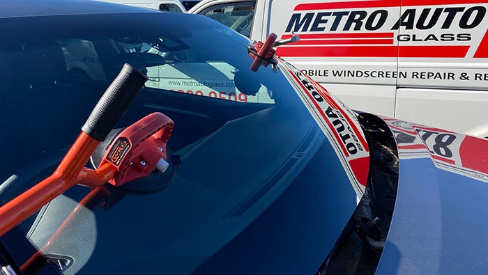 New windscreen glass being installed with Metro Auto Glass van in background