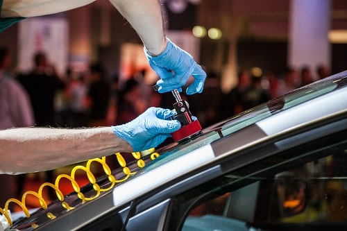 Auto glass technician using equipment to repair chip in windscreen.